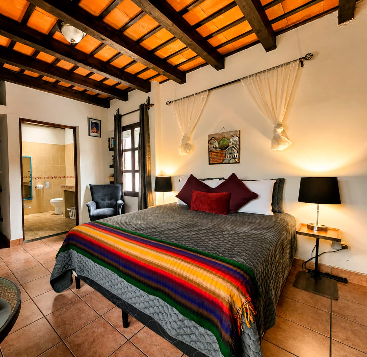 Cama queen de Condesa con textiles guatemaltecos bajo techo de madera y teja